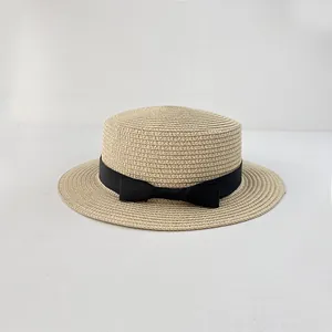 Detail of light beige boater hat with fine straw texture and black grosgrain bow