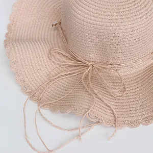 Detail eines rosa Strohhuts mit Webmuster, gewelltem Rand und dekorativem Schleifenband
