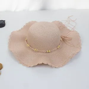 Detail eines rosa Strohhuts mit Perlenband und gewelltem Muschelrand-Design