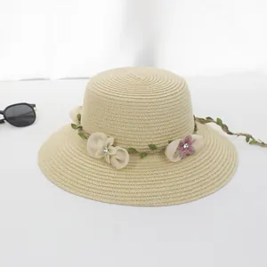 Detail eines Strohhuts mit dekorativer grüner Ranke und transparentem Blumenschmuck