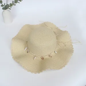 Detail eines beigen Strohhuts mit Wellenrand und natürlichen Muschelverzierungen