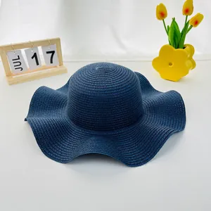 Detail of a dark blue wide-brim straw hat with wavy edges for summer sun protection