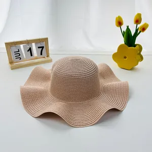 Detail of a beige woven straw sun hat with a wavy wide brim and fine summer texture