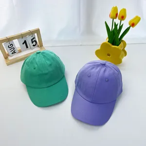 Kids plain cotton baseball caps in vibrant green and purple with curved brims