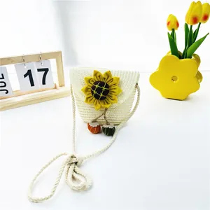 Detail der geflochtenen Kinder-Strohtasche mit gelber Sonnenblume und bunten Anhängern