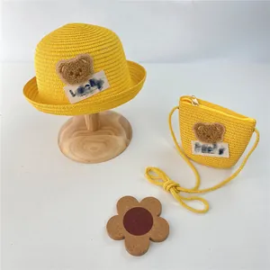 Detail of yellow straw sun hat and matching lucky bear crossbody bag for children