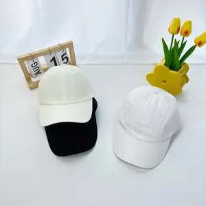 Close-up of cotton baseball caps in beige, black, and white with six-panel structure