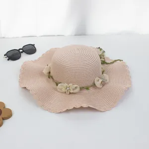 Detail eines Sommer-Strohhuts mit floraler Verzierung und stilvoller welliger Krempe