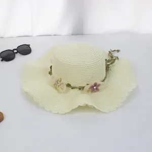 Detail eines Strohhuts mit Spitzenkante, Blumenverzierung und einer Sonnenbrille
