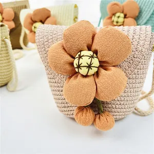 Detail von handgefertigten Stroh-Umhängetaschen mit Stoffblume und Bommel-Anhängern