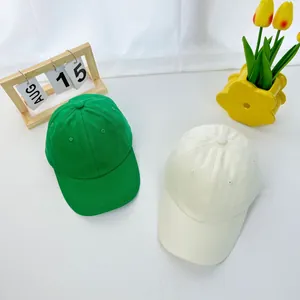 Top view of vibrant green and beige cotton twill baseball caps for kids on white surface