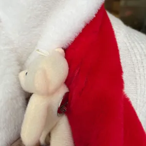 Close-up of a cute plush bear brooch pinned to a red and white warm winter scarf