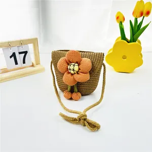 Nahaufnahme einer Strohtasche für Kinder mit auffälliger oranger Sonnenblumen-Verzierung