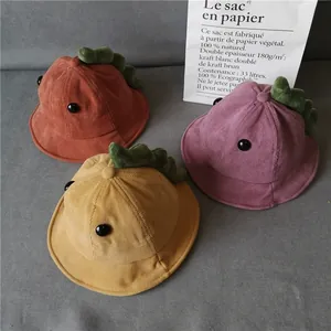 Detailed view of corduroy baby hats with 3D dinosaur spines in brick red and yellow