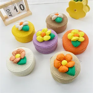 Détail de sacs ronds en paille pour enfants avec fleurs en tissu colorées et feuilles