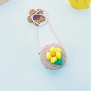 Détail d'un petit sac rond en paille pour filles avec une fleur en tissu jaune en 3D