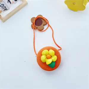 Détail d'un sac rond en paille orange avec une grande fleur de soleil pour filles