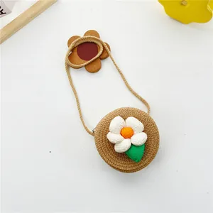 Détail d'un sac rond en paille marron pour filles avec fleur 3D et feuille verte