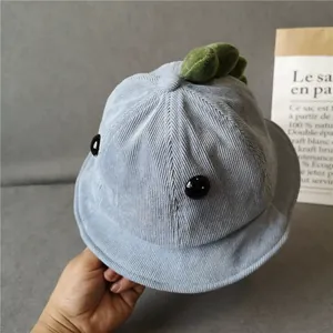 Close-up of light blue corduroy baby bucket hat with green plush dinosaur spikes