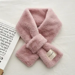 Détail d'une écharpe en fausse fourrure rose avec patch lettré et design croisé pratique