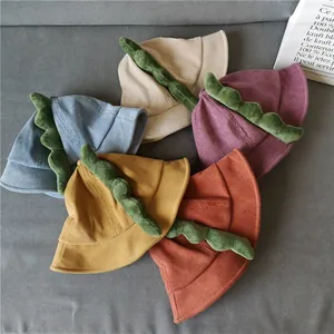 Flat lay of colorful corduroy kids bucket hats with plush 3D dinosaur spikes decoration