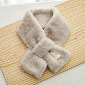 Gros plan du tour de cou en fausse fourrure beige avec design croisé et petite étiquette