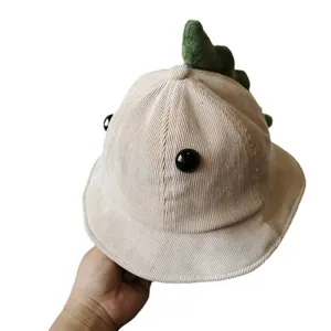 Beige corduroy kids bucket hat featuring cartoon dinosaur spikes and cute eye buttons