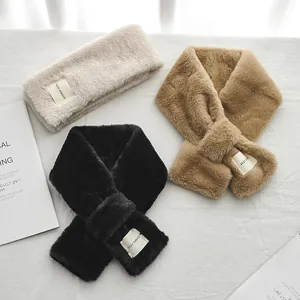 Détail de l'écharpe en peluche avec écusson à lettres et design croisé pratique