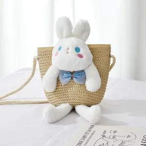 Detail of a handmade straw bag with a cute white plush rabbit and thick woven shoulder strap