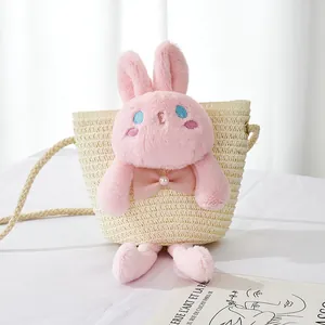 Detail of straw woven crossbody bag for girls featuring a cute pink plush bunny doll