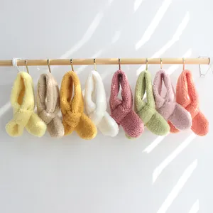 Plüsch-Lammwollschals für Kinder in vielen Macaron-Farben hängen an Holzstangen