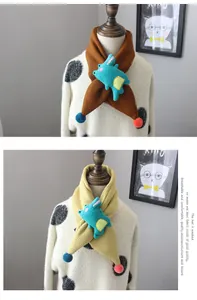 Detail of knitted children's scarves featuring plush blue dinosaur and colorful pom-poms