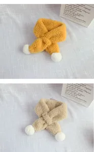 Detail of plush lamb wool cross scarf for kids with soft white pompoms in yellow and khaki
