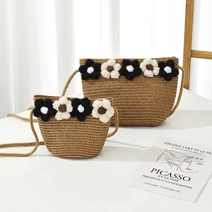Détail de deux sacs en paille tressée avec fleurs au crochet et fermeture éclair