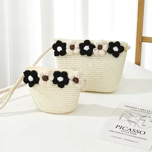 Détail de sacs en paille crème avec fleurs tissées et bandoulières en corde souple