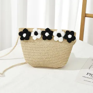 Détail d'un sac en paille tressée pour fille avec fleurs en tricot sur tissu blanc