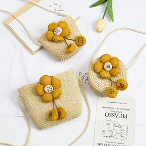 Detail van geweven stro mini-tasjes met grote gele bloemen en een dunne schouderriem