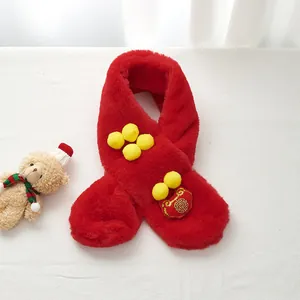 Detail of red plush kids scarf with yellow pom-poms and traditional Chinese embroidery