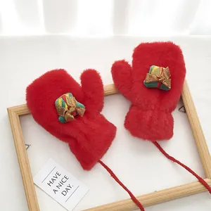 Detail of red plush mittens with a 3D gift box ornament and hanging neck string
