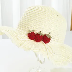 Détail d'un chapeau de paille pour filles avec écussons fraises et larges bords ondulés