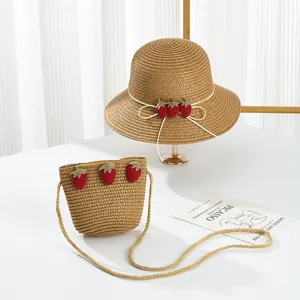 Detail of children's straw hat and matching bag with cute 3D strawberry decorations