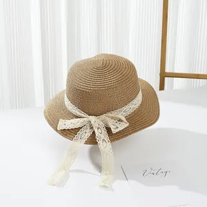 Straw sun hat with white lace bow on white table for elegant summer beach protection