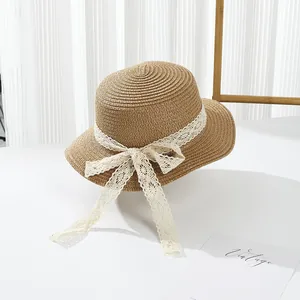 Detail of straw sun hat featuring elegant cream lace ribbon and a delicate bow tie