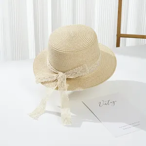Close-up of woven straw hat with vintage white lace ribbon and elegant bow detail