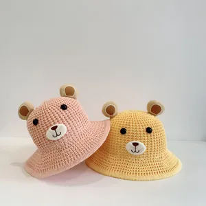 Détails de chapeaux de soleil en paille rose et jaune avec broderie de visage d'ours