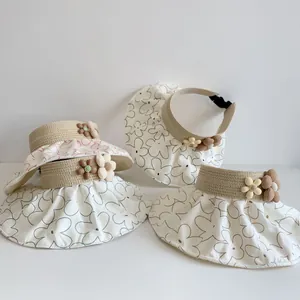 Detail of kids open top sun hat with woven straw brim and floral fabric crown detail