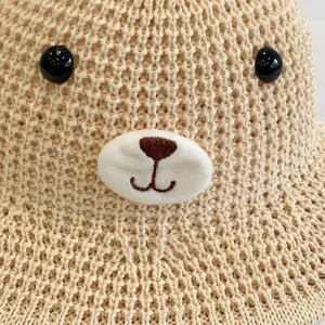 Détail d'un chapeau de paille beige au crochet avec visage d'ours et broderies mignonnes