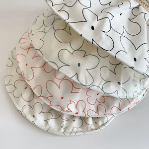 Detail view of four circular fabric coasters featuring colorful minimalist floral embroidery