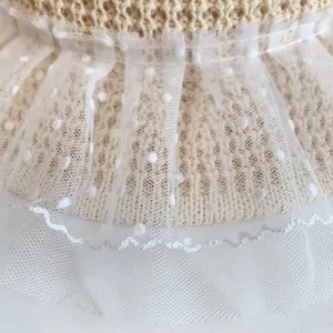 Macro detail of straw sun hat featuring beige weave and white polka dot lace trim