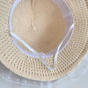 Detail of beige straw hat featuring white polka dot mesh lace and elastic wind rope
